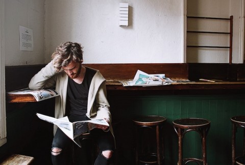 A person reads the newspaper looking troubled